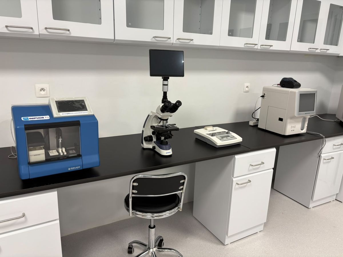 A laboratory bench with a haematology analyser, a microscope and a chemistry analyser