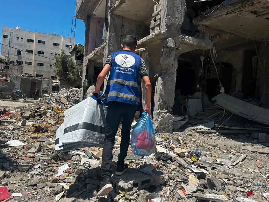 A Humanity First volunteer delivering a shelter kit amid the rubble in Gaza