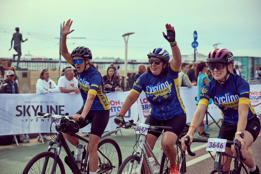 Three riders waving as they reach Brighton seafront