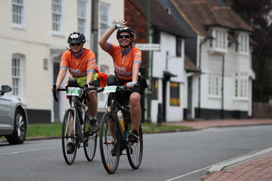 Riders passing white cottages in a village on the route to Brighton